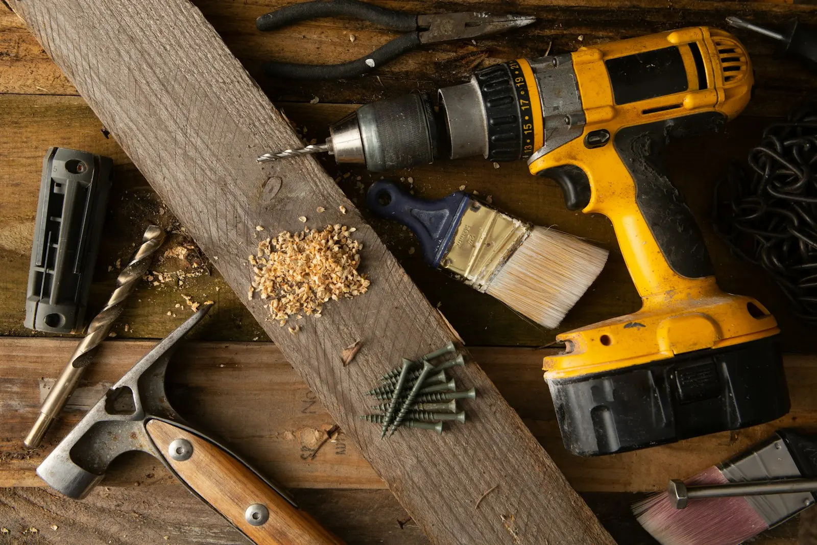 Akkuschrauber, Hammer und Werkzeuge auf Holz